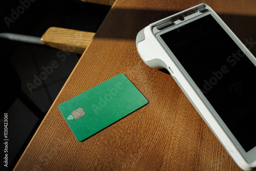 Modern payment terminal and credit cards on wooden background, top view. Space for text