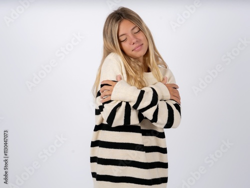 Beautiful teen girl wearing striped sweater  Hugging oneself happy and positive, smiling confident. Self love and self care photo