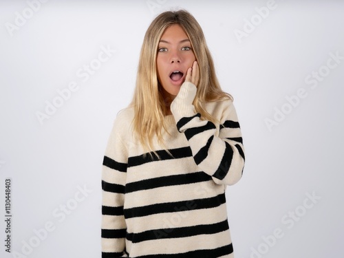 Shocked Beautiful teen girl wearing striped sweater looks with great surprisment being very stunned, astonished with unexpected news, Facial expressions concept. photo