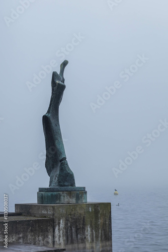 Statue at Zugersee lake shrouded in morning fog