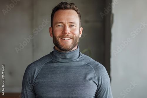 Portrait of a blissful man in his 30s showing off a lightweight base layer isolated on minimalist or empty room background