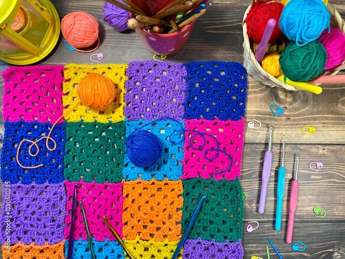 Crocheted granny square sample and colorful multicolor clews balls of yarn handmade handiwork craft home decor photo coxy picture autumn fall winter vibe with flashlight candle photo