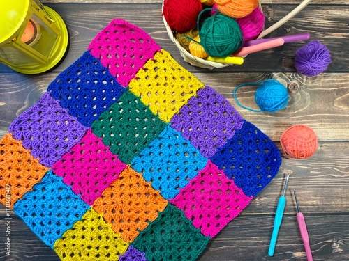 Crocheted granny square sample and colorful multicolor clews balls of yarn handmade handiwork craft home decor photo coxy picture autumn fall winter vibe with flashlight candle photo