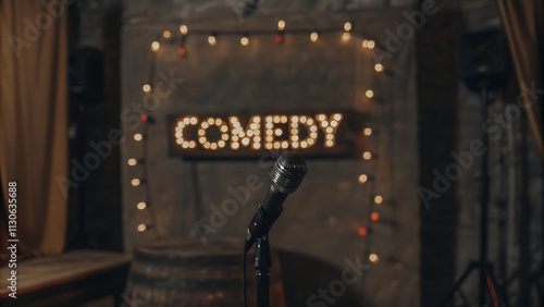 A microphone on a stand in front of a comedy sign with warm lights. The background is a rustic, dimly lit stage setting. Perfect for comedy shows.