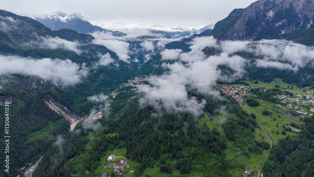 Obraz premium Mountain Serenity: Aerial View of a Scenic Village Amidst Clouds and Peaks