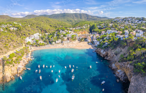 Aerial view of Cala Vadella, Ibiza, showcasing turquoise waters, sailboats, sandy beaches, and luxury villas photo