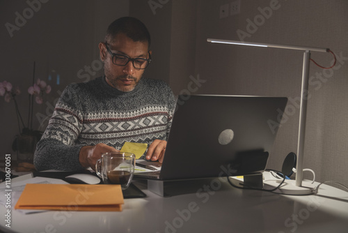 A man is sitting at a desk with a laptop and a cup of coffee. Remote work concept