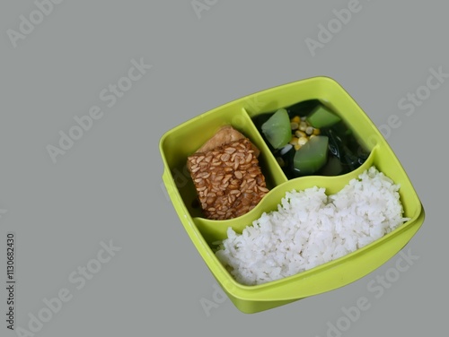 A balanced and nutritious meal of rice, tempeh, spinach, and squash, packed in a lunch box, ideal for students and office workers, free lunch for student programmed by Indonesia president Prabowo photo