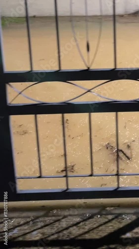 This video captures the aftermath of a thunderstorm, showing the road submerged in water as the river overflows. The once-contained river has flooded, covering the street with rising water. photo