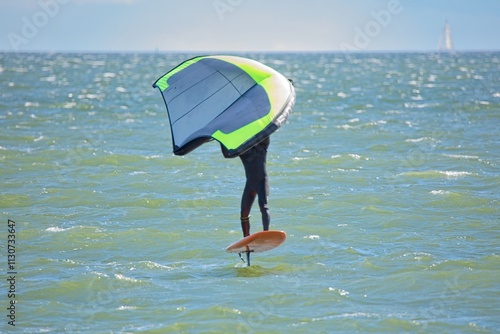 Canvas Print Man is wing foiling using handheld inflatable wing and hydrofoil surfboard in sea in summer