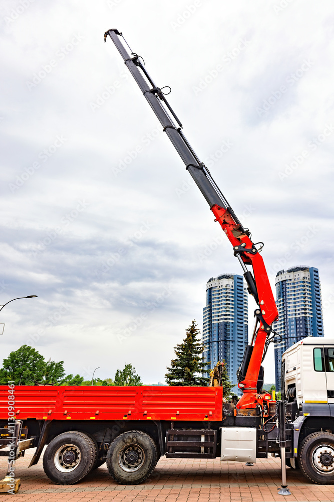 Towering crane reaches towards the cloudy sky above a busy urban construction site