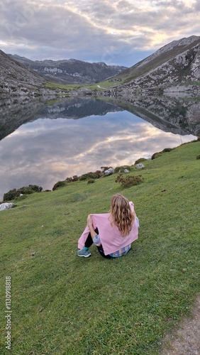 woman sitting on a grass in front of lake