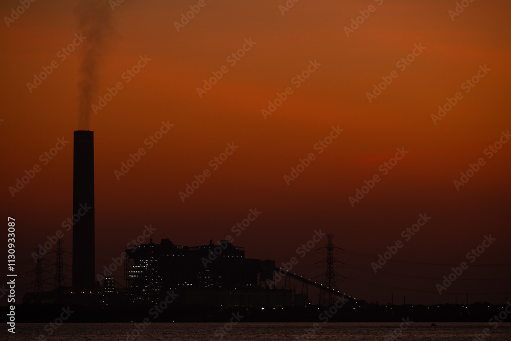Obraz premium Night of Industrial skyline with smokestack emissions shows urban pollution, climate change, and environmental impact. The silhouette emphasizes air pollution and the need for sustainable solutions.