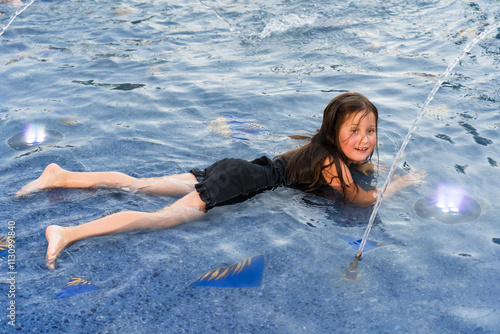 A little girl bathes in a fountain on a summer day. The action takes place in the south of France, on a summer day in Cannes. photo