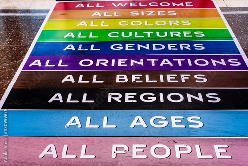 Very big lgbtq Welcome sign explains the colors of the flag. All sizes, colors, cultures, sexes, genders, beliefs, religions, ages, people.