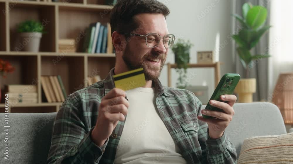 Caucasian man male guy at home happy smiling positive glad buying purchase shopping buy online with bank mobile phone using smartphone order food delivery booking payment kiss credit card kissing