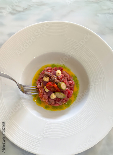 Modern style gourmet raw beef fillet tartare with cappei egg and dried tomato photo