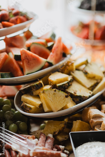 Vibrant Watermelon and Pineapple Slices on an Elegant Grazing Table Display with Fresh Fruit, Cheese, and Charcuterie for Upscale Events, Weddings, and Catering Inspiration