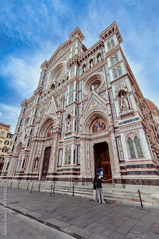 Young tourists admire the intricate facade of Santa Maria del Fiore Cathedral in Florence.