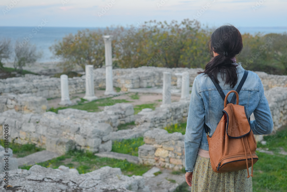 A young tourist stands against the backdrop of the ruins of ancient Chersonesus in Sevastopol in Crimea. Travel concept.