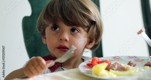 Toddler kid eating lunch sititng at table photo