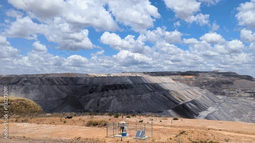 Coalmine slow panoramic, Mining industry equipment and vehicles, a view of the large pit, with a cloud scattered sky. 4k stock video. Collie, western Australia 