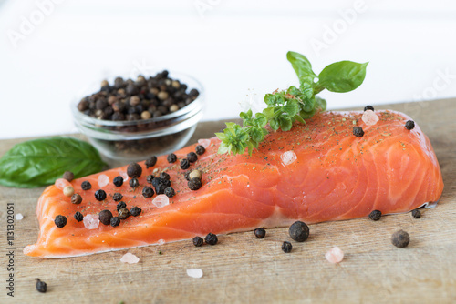 Raw salmon steak on a wooden background with spices. Top view of red fish fillet with aromatic spices.