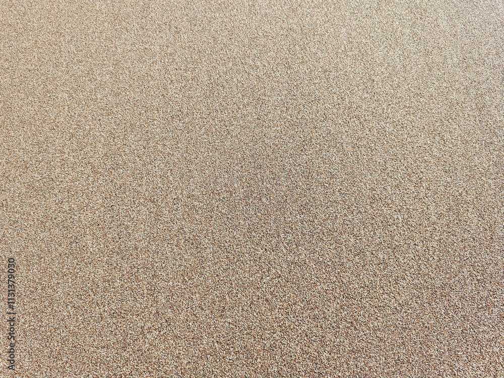 Detailed close-up photograph of fine golden sand grains, captured under natural lighting. The image highlights the intricate textures and patterns of the sand.