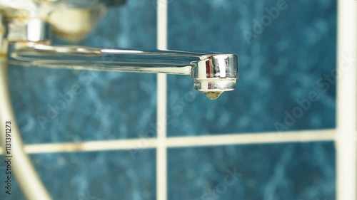 A drop of water drips from a leaky faucet