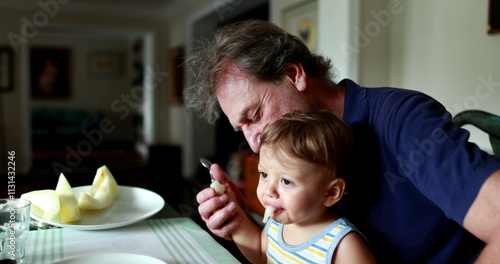 Billede på lærred Baby spitting food out, toddler spits fruit on grand-father lap