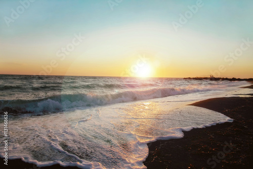 Sunrise on sandy beach against the backdrop of waves.