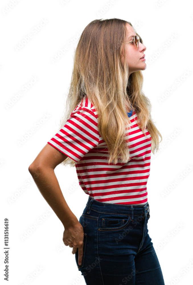 Young beautiful blonde woman wearing sunglasses over isolated background looking to side, relax profile pose with natural face with confident smile. Young beautiful blonde woman wearing sunglasses over isolated background looking to side, relax profile pose with natural face with confident smile.