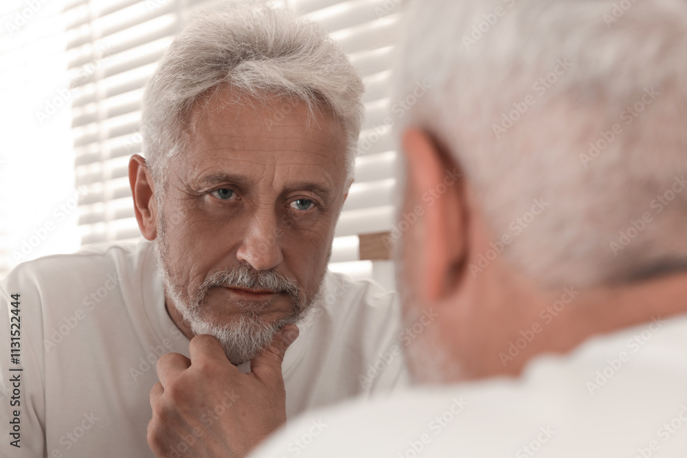 Fototapeta premium Senior man looking in mirror at home