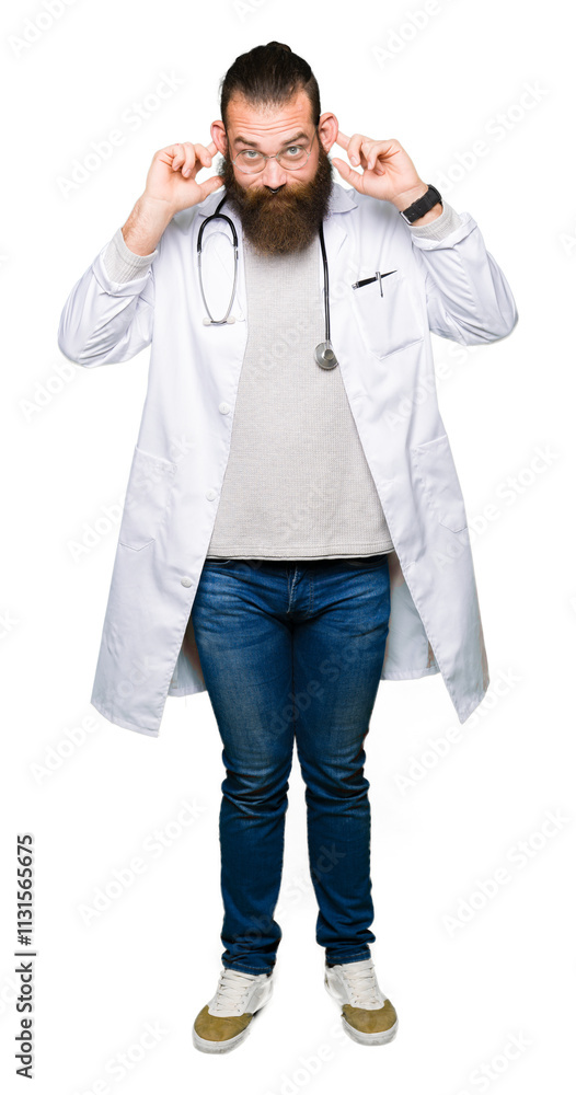 Φωτογραφία Young blond doctor man with beard wearing medical coat Smiling pulling ears with fingers, funny gesture