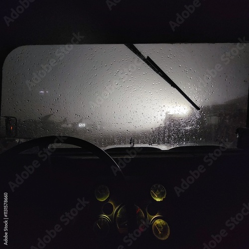 Rain dripping on a car windshield in the dark