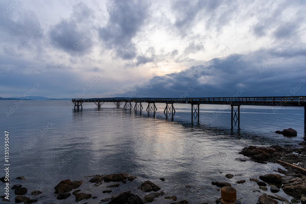 Obraz premium Scenic View of a Coastal Pier at Sunset with Tranquil Waters