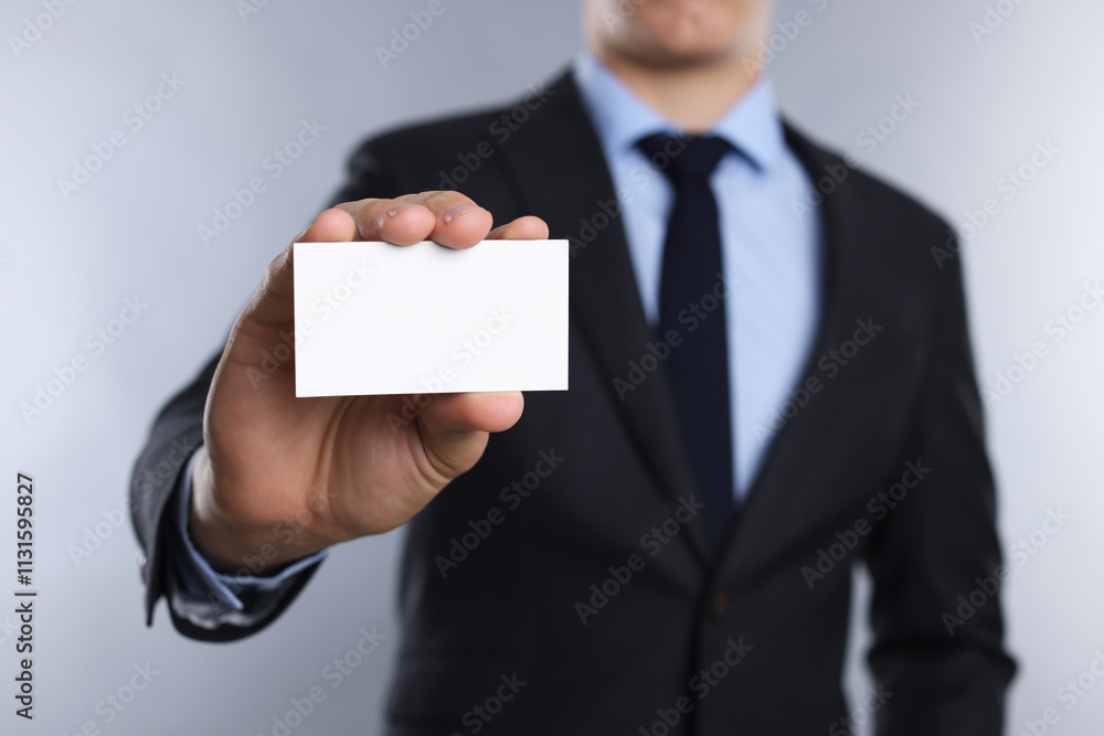 Fototapeta premium Man holding blank business card on grey background, closeup. Mockup for design