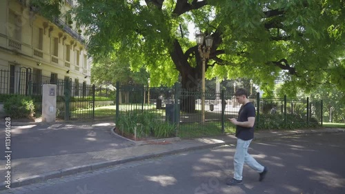 Wallpaper Mural young latin man walking around the city, chatting on his cell phone while walking, full body Torontodigital.ca