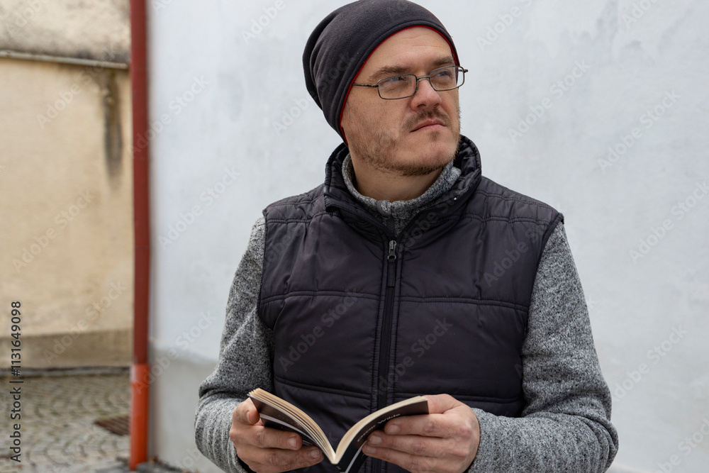 A man with a book on the street.