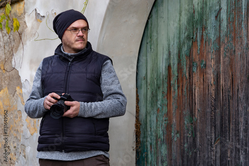 A man with a camera walking through an autumn city.