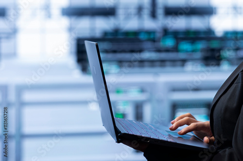 Software developer in data center making sure rackmounts are functioning optimally. Close up of specialist in server farm using laptop to monitor energy consumption across supercomputer rigs. photo