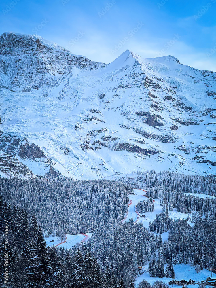 Scenic view of snowcovered Silberhorn mountain (right) and Lauberhorn ski racing downhill slope in Wengen, Switzerland against blue sky in winter