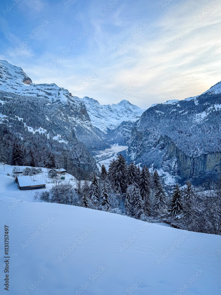 Panoramic view of Lauterbrunnen Valley, Switzerland seen from Wengen with snowcovered Breithorn mountain in winter against blue sky with clouds