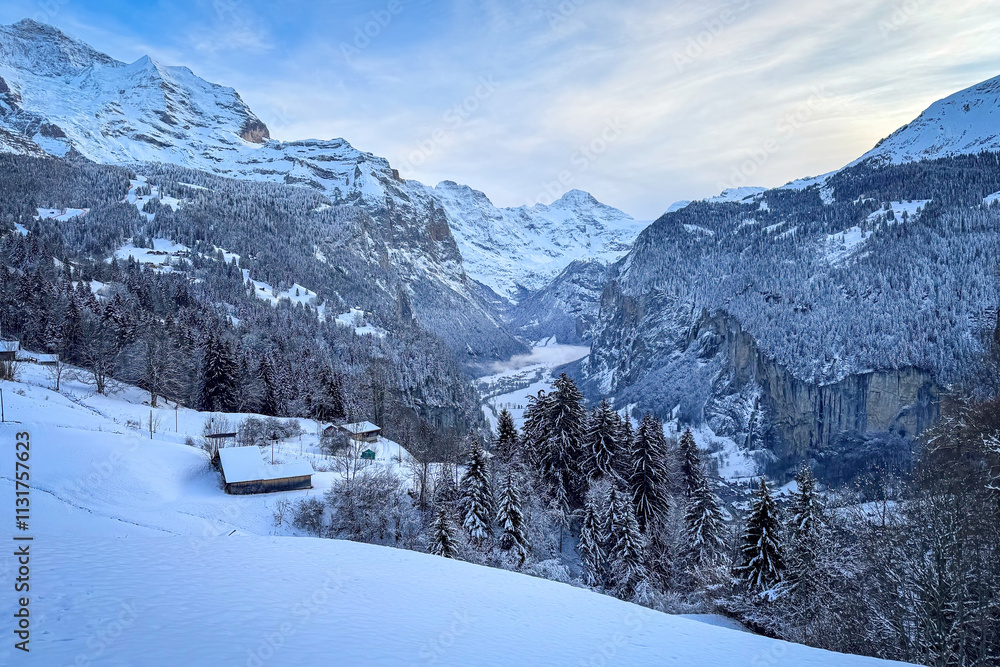 Panoramic view of Lauterbrunnen Valley, Switzerland seen from Wengen with snowcovered Breithorn (middle) and Jungfrau (left) mountain in winter against blue sky with clouds