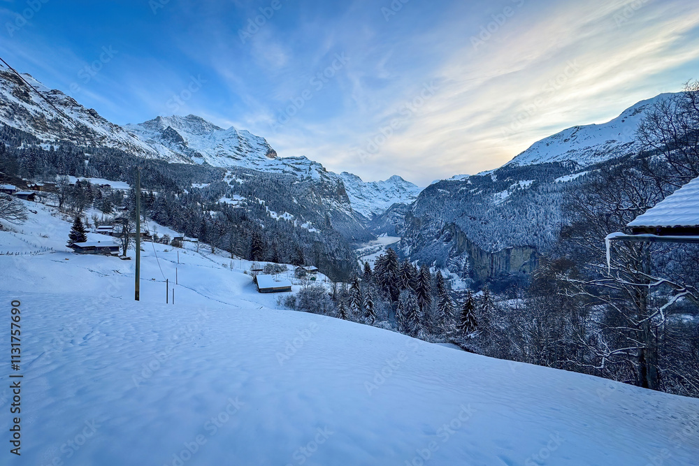 Panoramic view of Lauterbrunnen Valley, Switzerland seen from Wengen with snowcovered Breithorn (middle) and Jungfrau (left) mountain in winter against blue sky with clouds