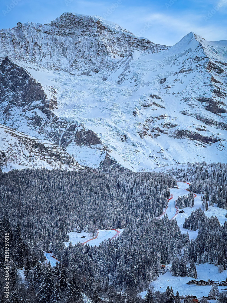 Scenic view of snowcovered Jungfrau (left) and Silberhorn mountain above Lauberhorn ski racing downhill slope in Wengen, Switzerland against blue sky