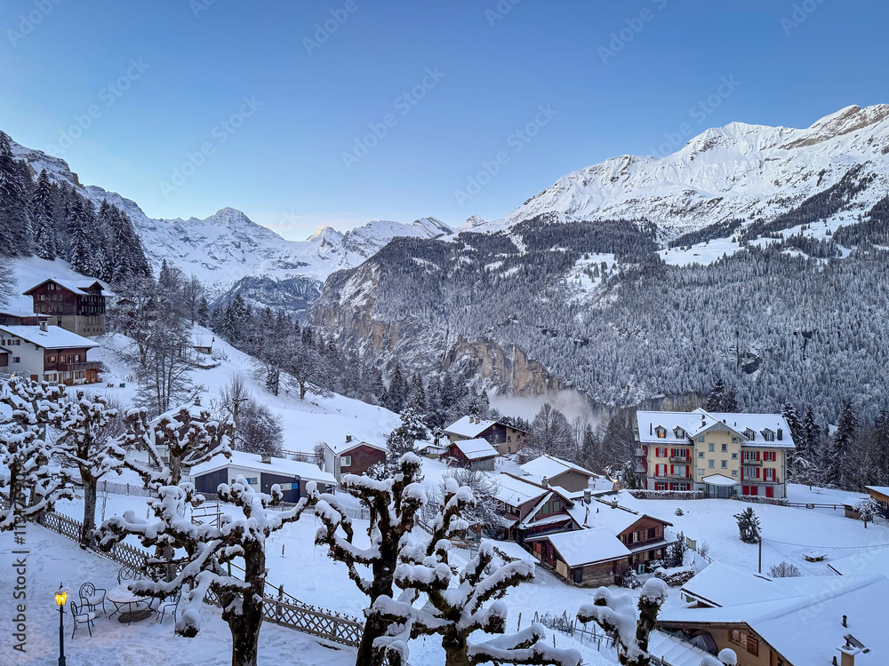 Scenic view of Wengen and Lauterbrunnen Valley, Switzerland with snowcovered mountains in winter against blue sky at sunset