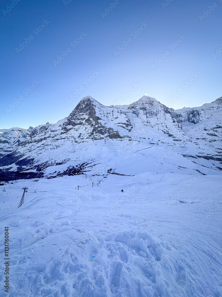 Scenic view of snowcovered Eiger and Moench mountains in Switzerland early in the morning against blue sky