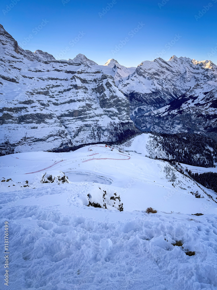Panoramic view of upper Lauberhorn Ski World Cup race course against snowcapped mountains in Wengen, Switzerland on a beautiful morning with blue sky