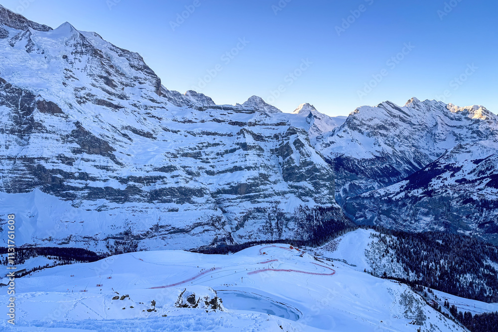 Panoramic view of upper Lauberhorn Ski World Cup race course against snowcapped mountains in Wengen, Switzerland on a beautiful morning with blue sky